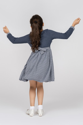 Back view of a little girl in a blue dress and white shoes
