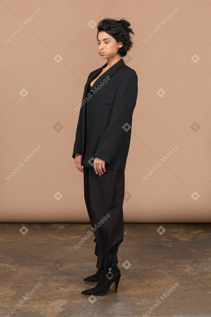 Three-quarter view of a businesswoman in a black suit pouting with her eyes closed