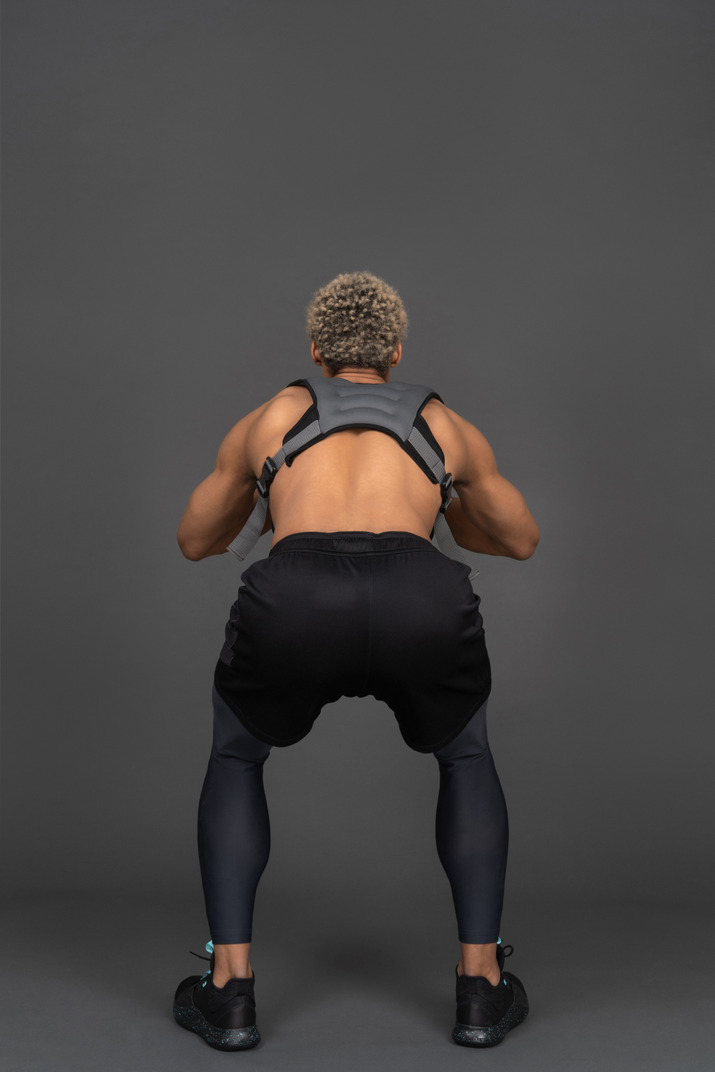 Back view of a shirtless squatting afro man