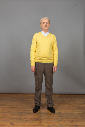 Front view of an old man wearing yellow pullover and standing still