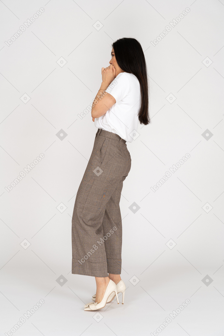 Side view of a scared young lady in breeches and t-shirt touching her mouth