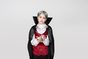 Boy in vampire costume holding candies