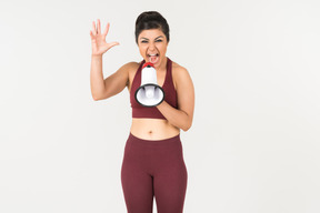 Angry looking young indian woman screaming using megaphone