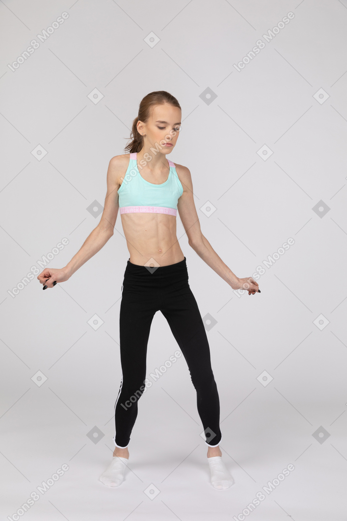 Front view of a teen girl in sportswear dancing while outstretching her arms