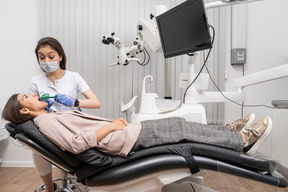 Toute la longueur d'une femme dentiste faisant un dossier dentaire à sa patiente dans une armoire d'hôpital