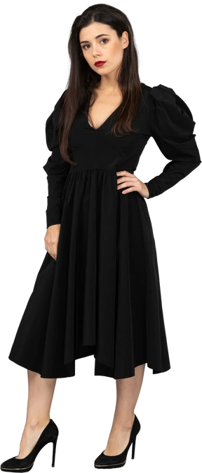Three-quarter view of a young lady in a black dress putting hand on hip