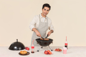 Jeune homme de race blanche concentré sur la cuisson barbecue