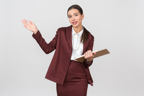 Atraente mulher formalmente vestida com uma prancheta apontando para algo