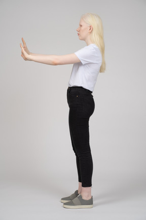 Side view of a young girl standing and reaching out her arms