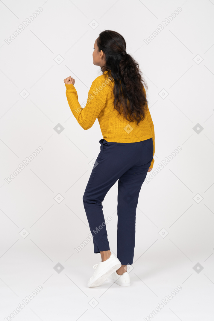 Rear view of a girl in casual clothes showing fist