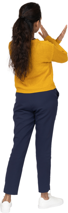 Rear view of a girl in casual clothes making stop gesture