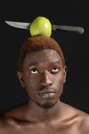 Portrait of an african male with an apple pierced with knife on his head