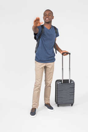 Male tourist holding luggage and pointing forward
