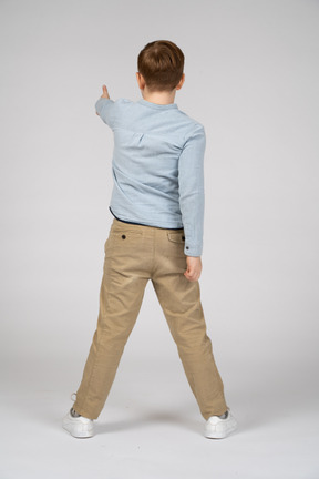 Vista traseira de um menino mostrando o polegar