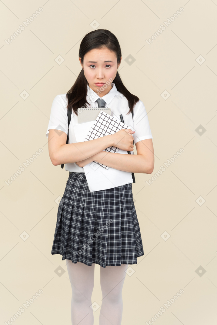 Sad looking asian school girl holding notes