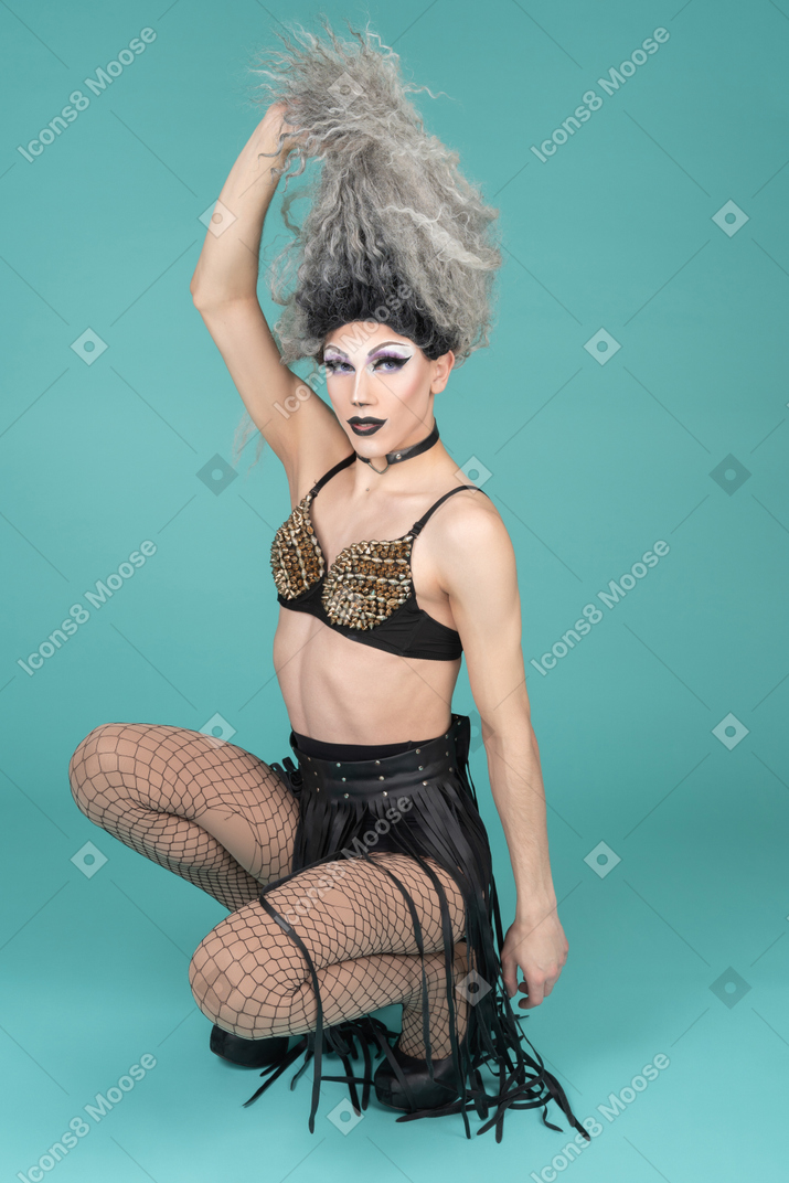 Drag queen squatting and pulling up hair