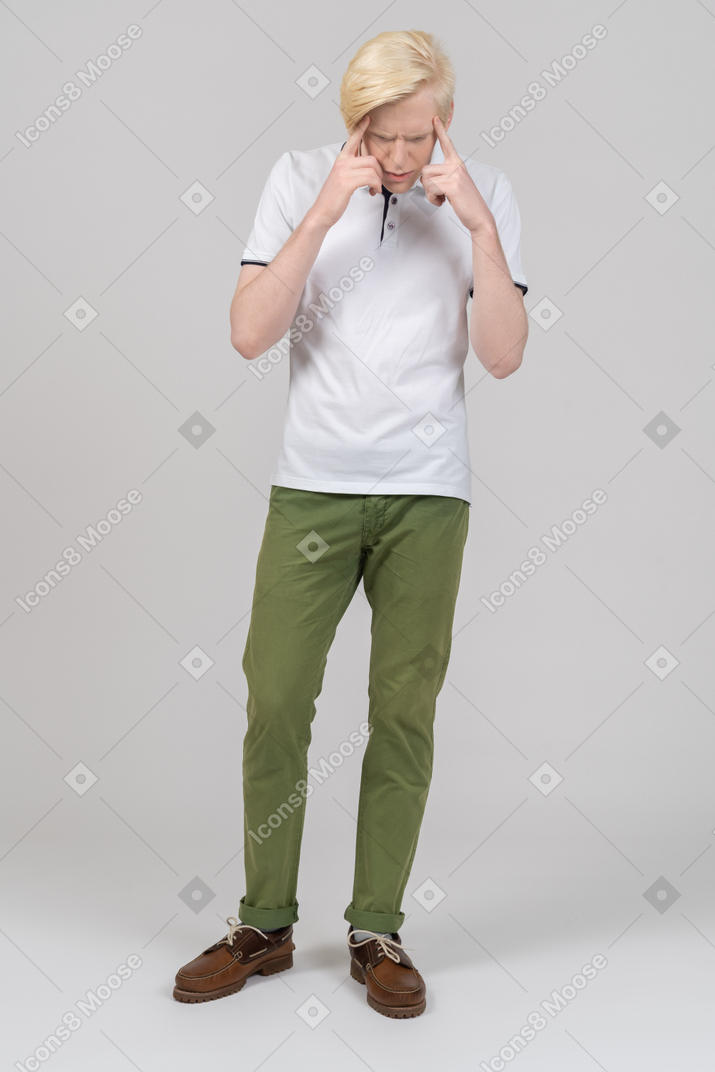 Молодой человек, держащий пальцы на висках