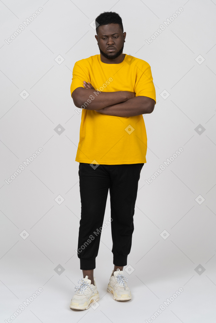 腕を組んで黄色のtシャツを着た若い浅黒い肌の男の正面図