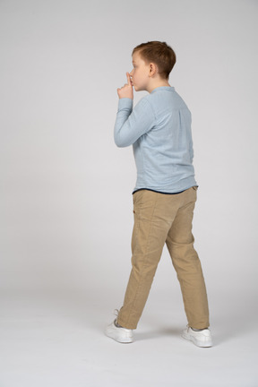 Vista traseira de um menino fazendo gesto de shhh