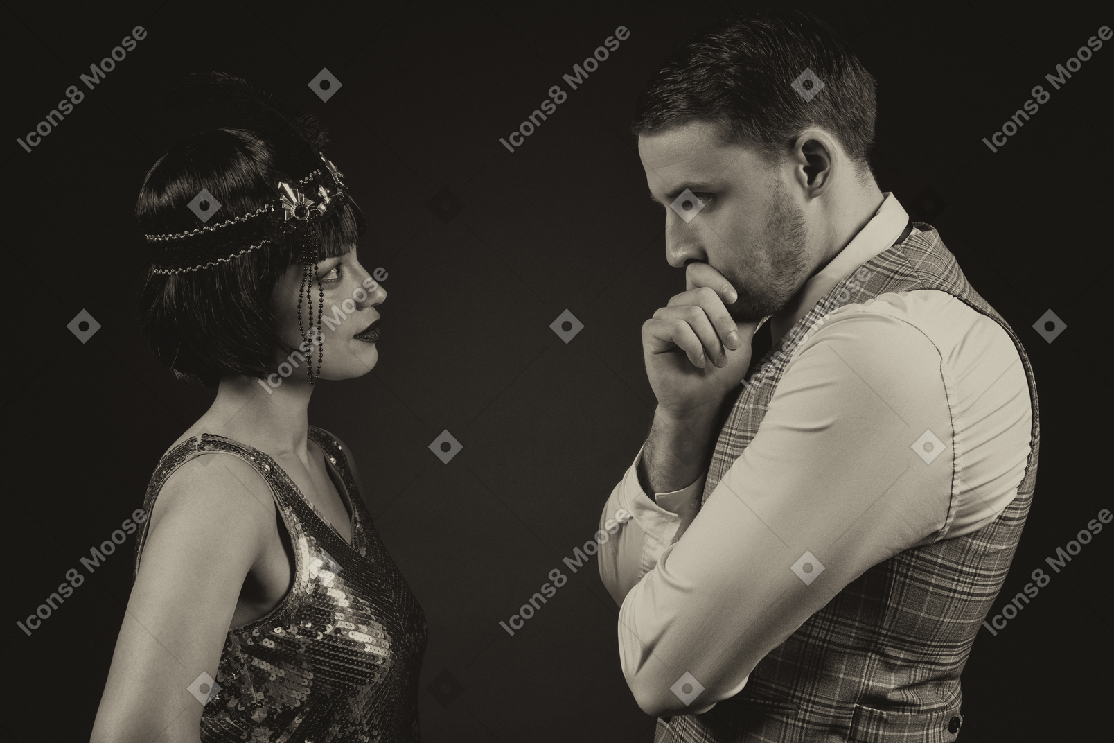 Well-dressed man and woman looking at each other isolated over black background