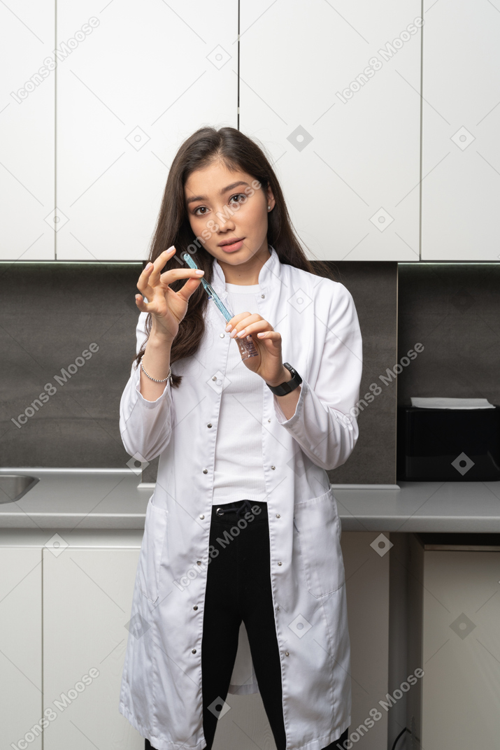Вид спереди стоматолога-женщины, внимательно держащего зубную щетку и смотрящего в камеру
