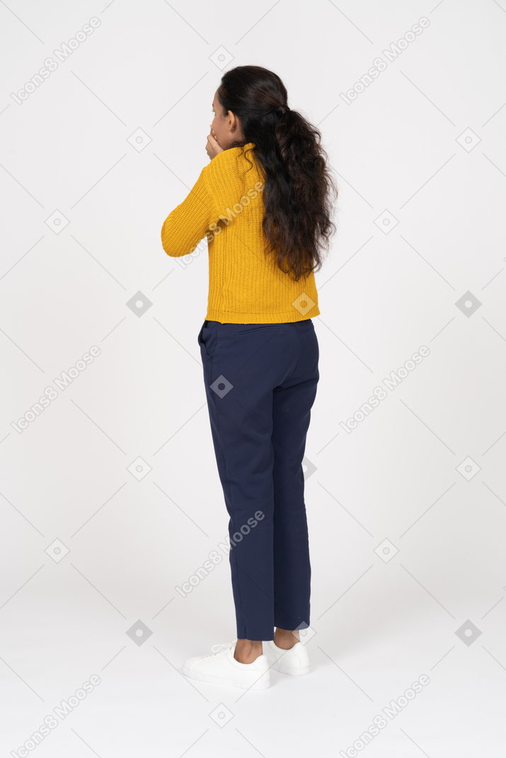 Vista trasera de una niña en ropa casual cubriendo la boca con las manos