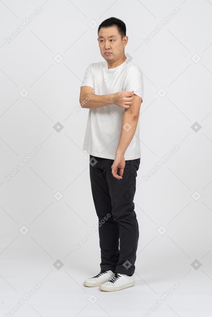 Вид в три четверти на мужчину в повседневной одежде, поправляющего рукав футболки