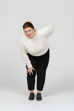 Mulher plus size com roupas casuais, sofrendo de dores na parte inferior das costas