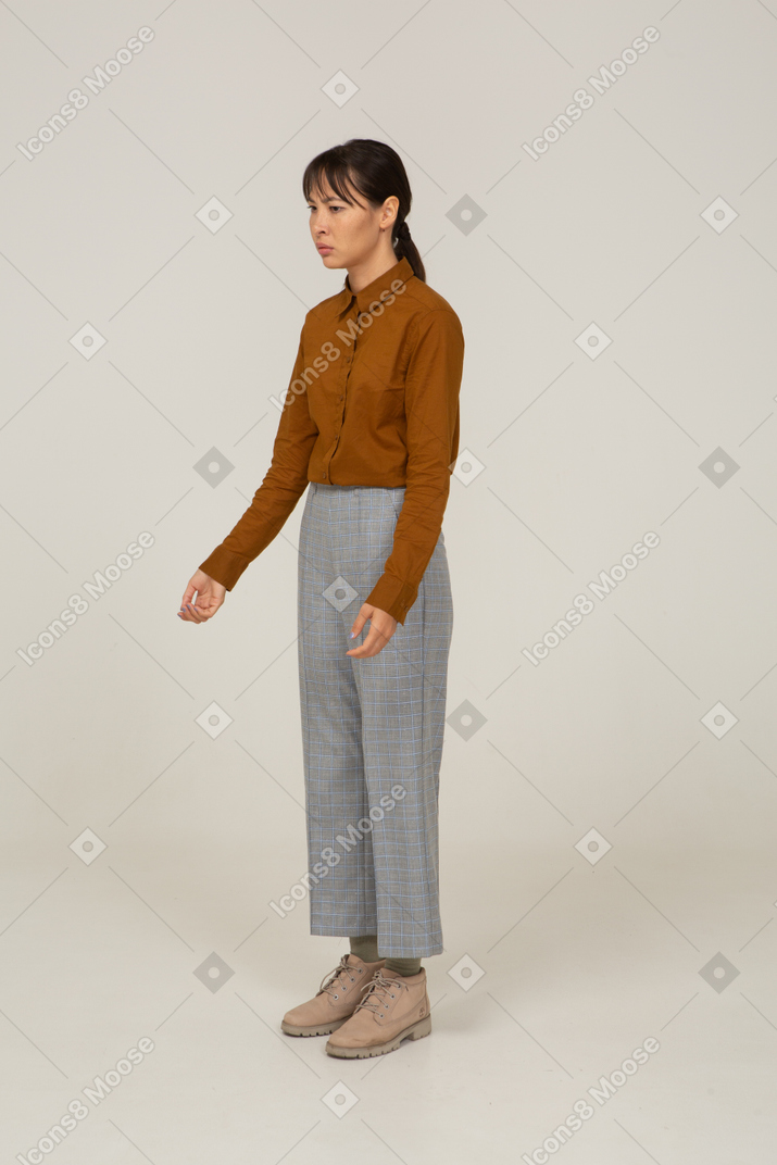 Three-quarter view of a perplexed young asian female in breeches and blouse
