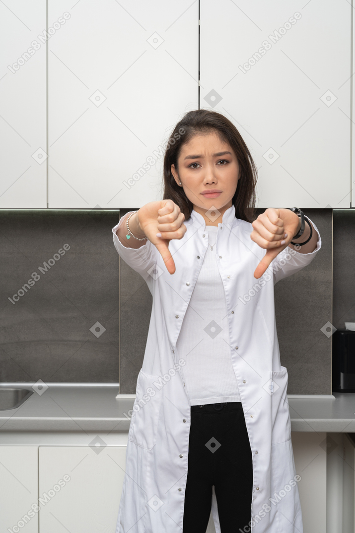 Front view of a female doctor showing a dislike gesture with both her hands