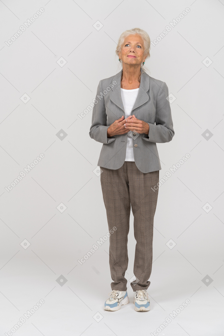Vista frontale di una vecchia signora in abito che guarda in alto