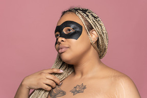 Black woman in eye mask looking at transparent mirror