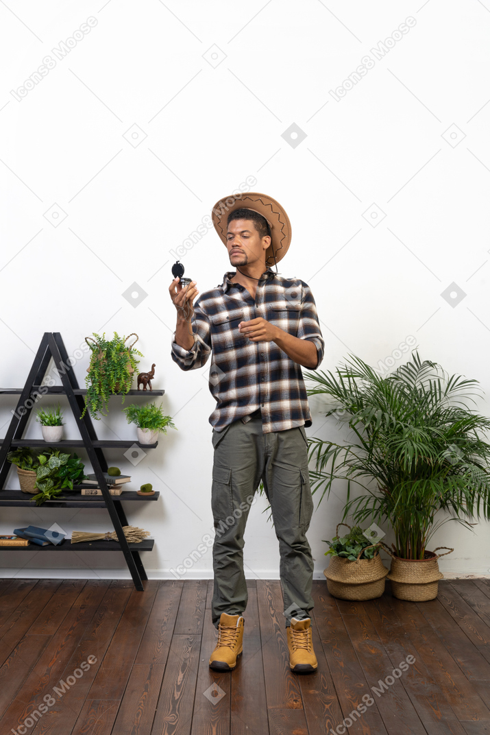 Dreiviertelansicht eines touristen mit cowboyhut, der auf einen kompass blickt