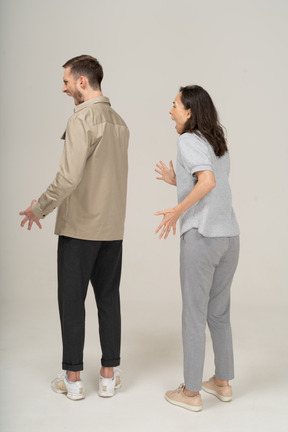 Three-quarter back view of young couple being mad and shouting