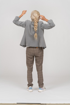 Back view of an old lady in suit standing with raised hands