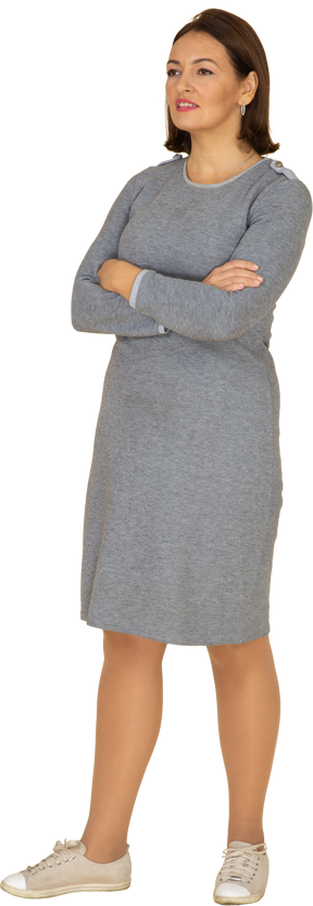 一个穿着灰色连衣裙的女人双臂交叉站立的前视图