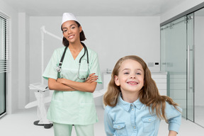 A young girl is standing next to a nurse in a dental office