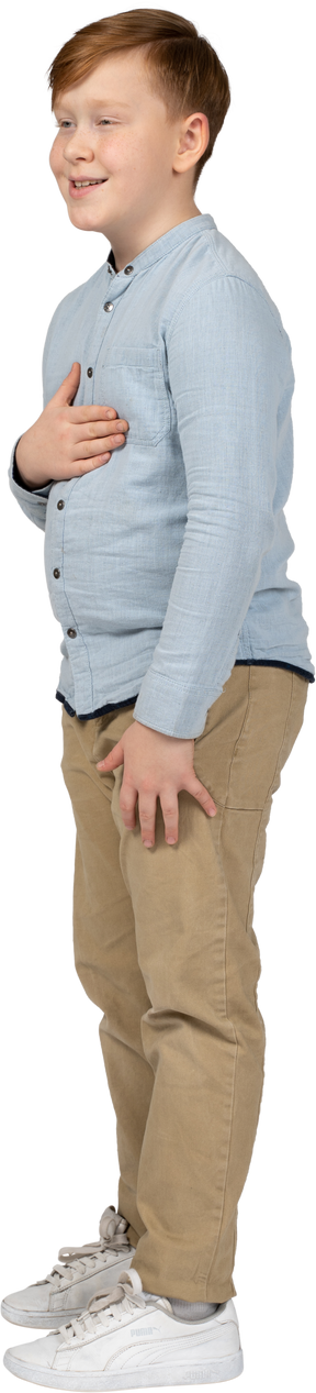 Side view of a cute boy posing with hand on chest