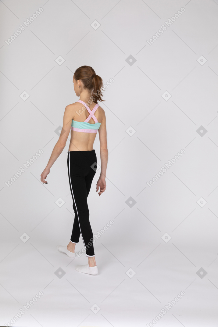 Three-quarter back view of a teen girl in sportswear walking away