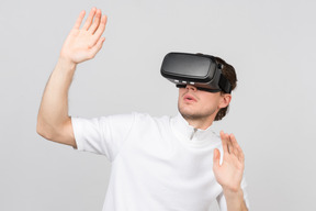 Man in virtual reality headset standing with his hands raised in surrender