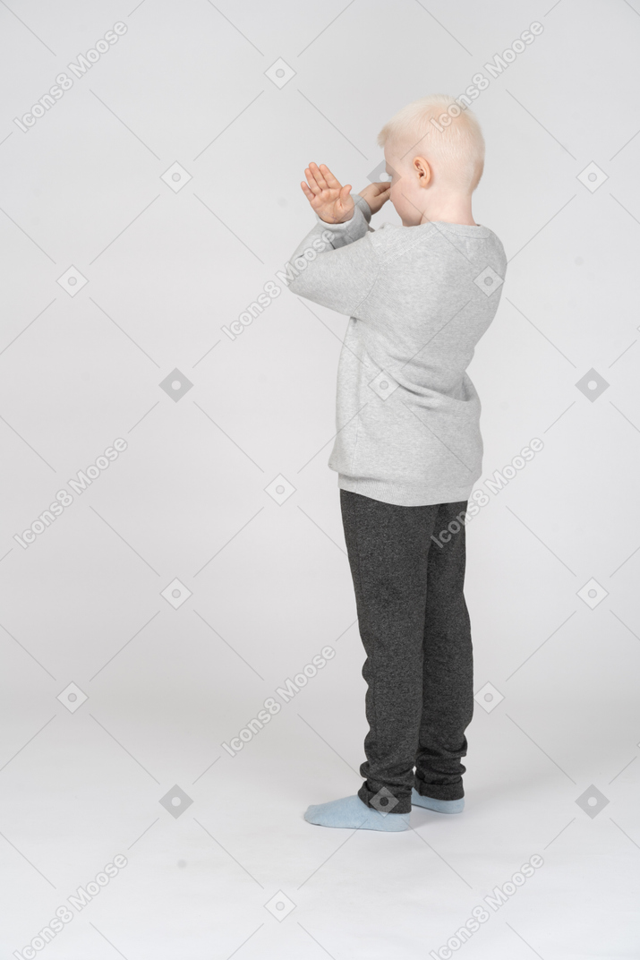 一个小男孩双手交叉的四分之三后视图