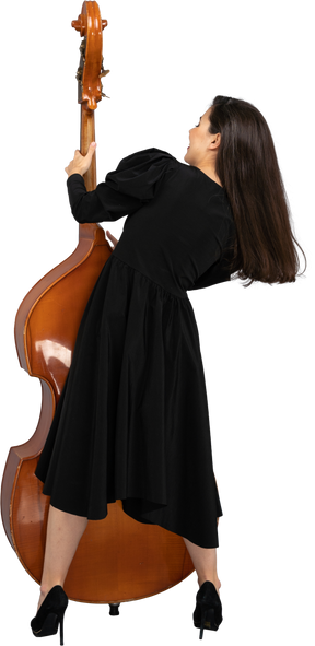 彼女のコントラバスを保持している黒いドレスを着た若い女性ミュージシャンの背面図
