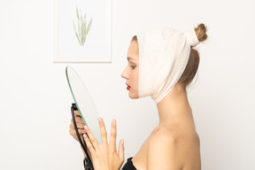 Side view of a young woman holding a mirror