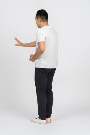 Вид в три четверти на человека в повседневной одежде, стоящего с вытянутой рукой