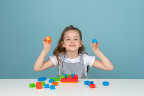 Niña sosteniendo un bloque de construcción naranja y azul