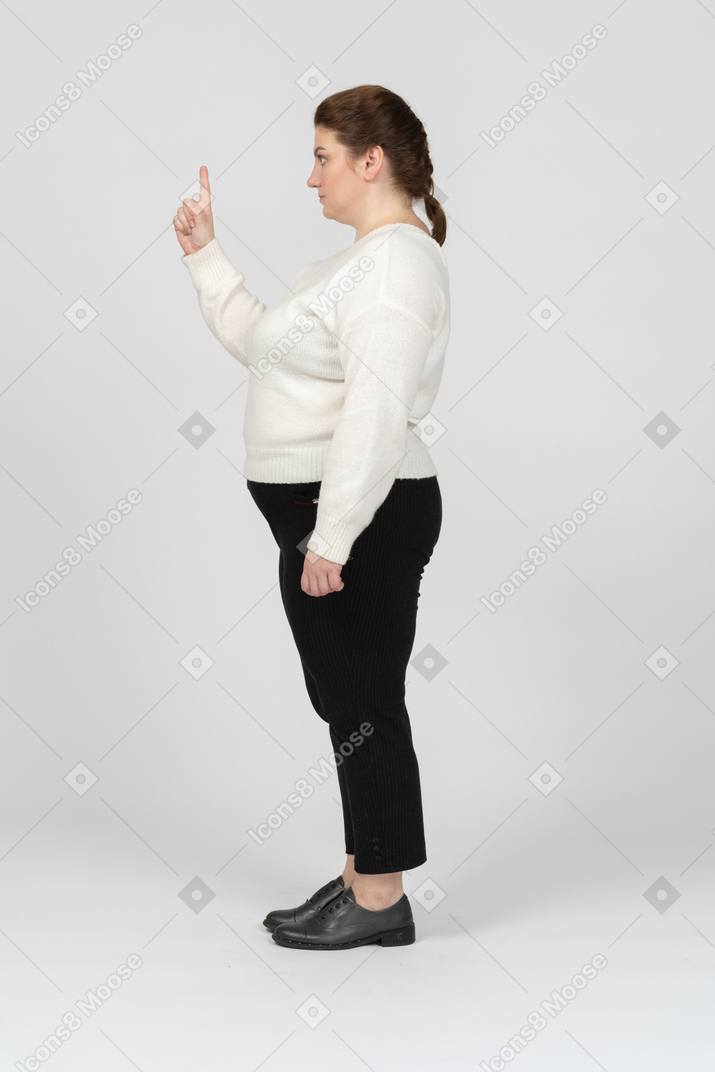 Femme de taille plus dans des vêtements décontractés pointant vers le haut avec un doigt
