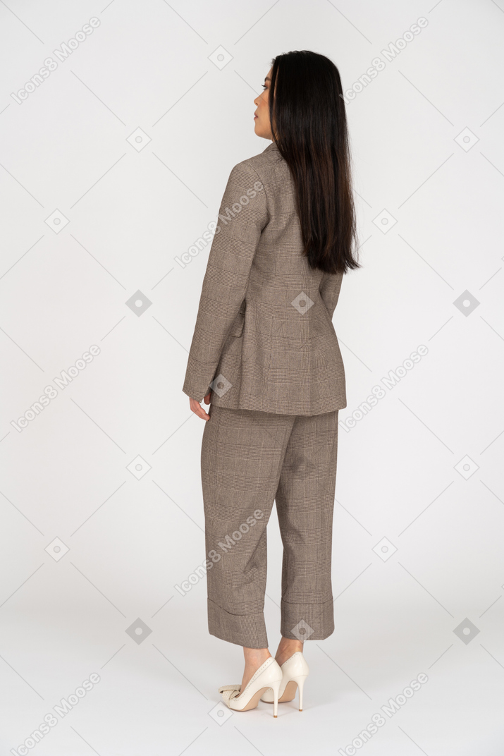 Three-quarter back view of a young lady in brown business suit