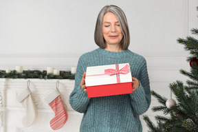 Ältere frau bereit, eine weihnachtsgeschenkbox zu öffnen
