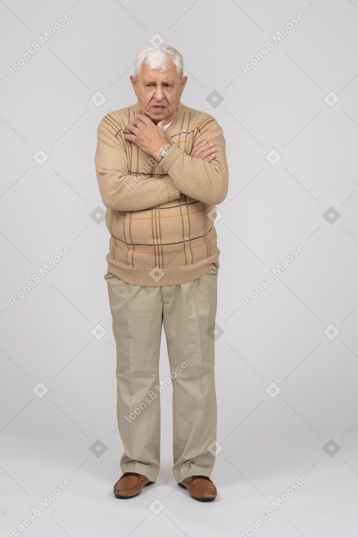 Front view of an old man in casual clothes standing with hand on shoulder