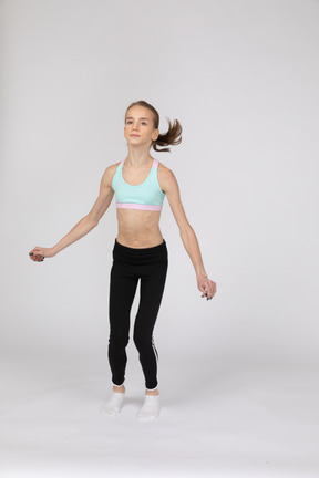 Side view of a teen girl in sportswear squatting and putting hands on hips